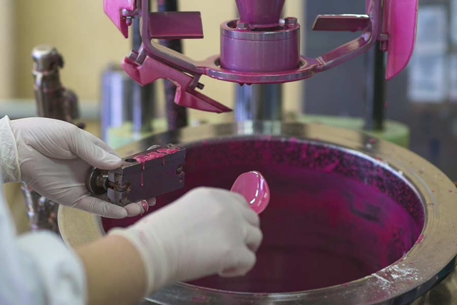 Zwei Hände mit Handschuhen, die eine pinke Farbe mit Hilfe eines Farbmischgerätes anrühren.